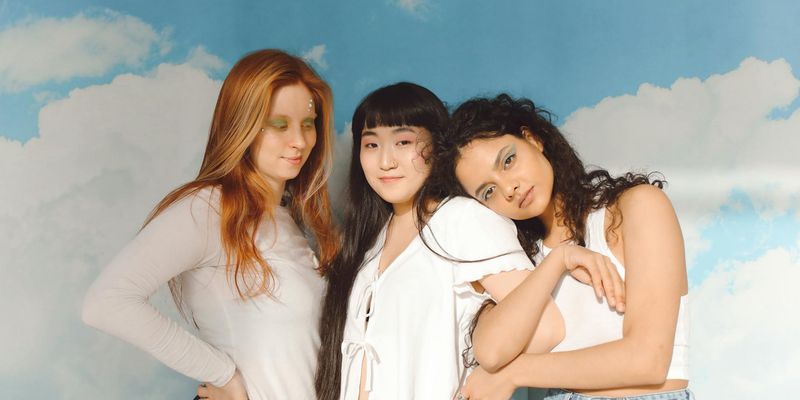 A diverse group of women smiling and supporting each other in a bright space.